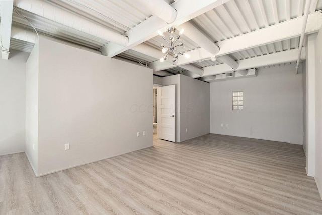 below grade area featuring light wood-style flooring and a notable chandelier
