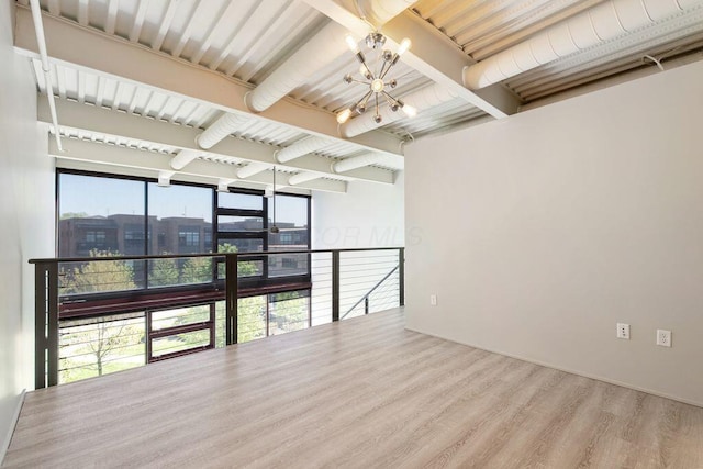empty room featuring an inviting chandelier, wood finished floors, and a healthy amount of sunlight