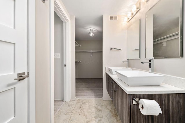 bathroom featuring visible vents, a sink, and a spacious closet