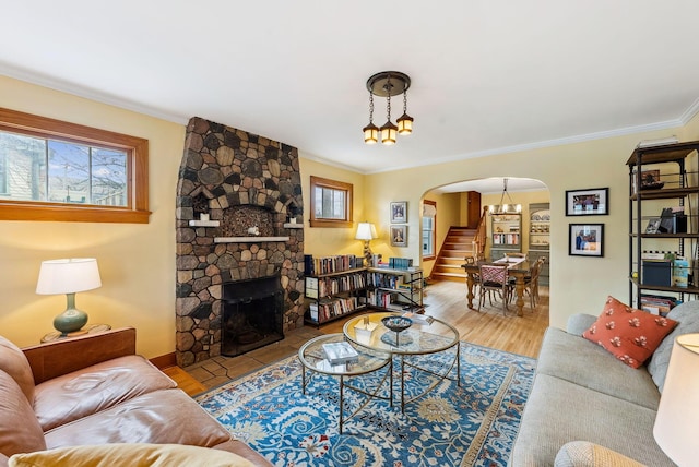 living room with arched walkways, a fireplace, wood finished floors, stairway, and crown molding