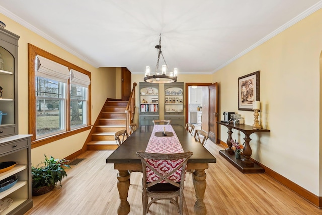 dining area with a chandelier, crown molding, light wood-style flooring, and stairs