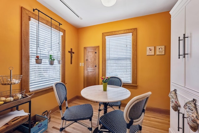 dining area with a healthy amount of sunlight, light wood-style flooring, and baseboards