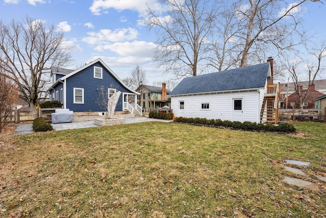 rear view of house featuring a yard, a patio area, fence, and stairway