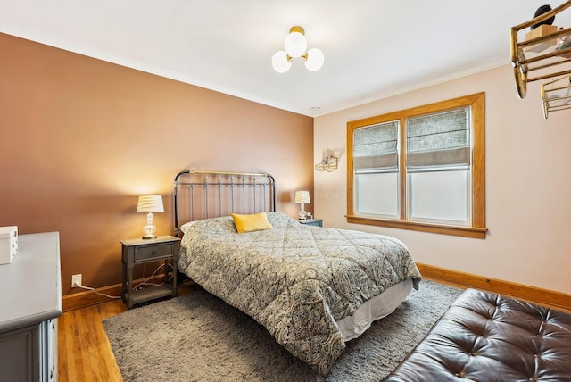 bedroom with crown molding, wood finished floors, and baseboards