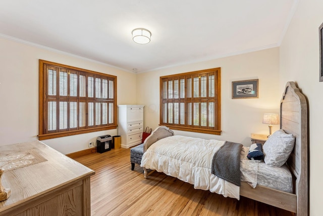 bedroom featuring light wood finished floors, baseboards, and crown molding