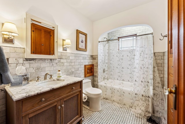 bathroom featuring wainscoting, toilet, shower / tub combo with curtain, vanity, and tile walls