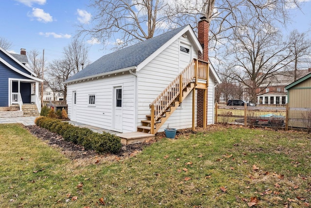 view of home's exterior with a yard, a chimney, fence, and roof with shingles