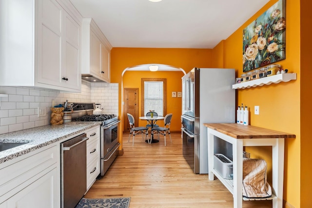 kitchen with stainless steel appliances, white cabinetry, and light wood-style floors