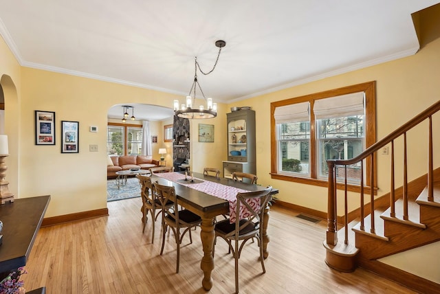 dining room featuring arched walkways, stairway, light wood-type flooring, and visible vents