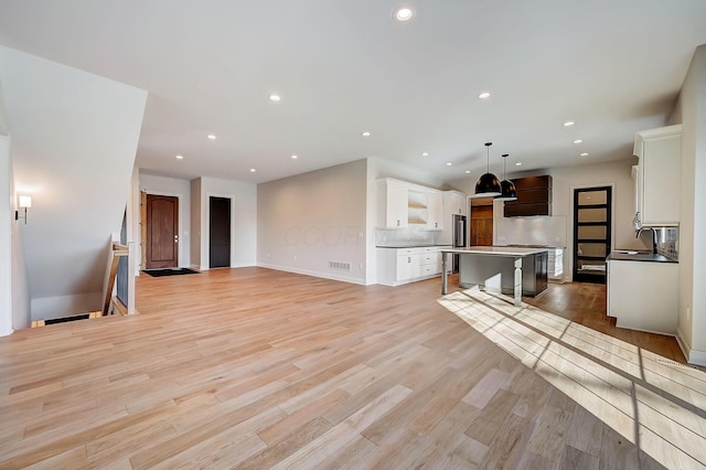 living area featuring light wood-type flooring, visible vents, baseboards, and recessed lighting