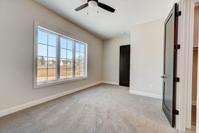 unfurnished bedroom featuring light colored carpet, ceiling fan, visible vents, and baseboards