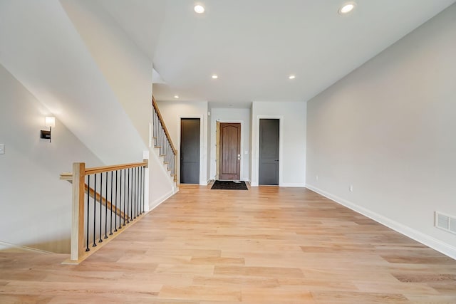 empty room with baseboards, visible vents, light wood-style flooring, stairs, and recessed lighting