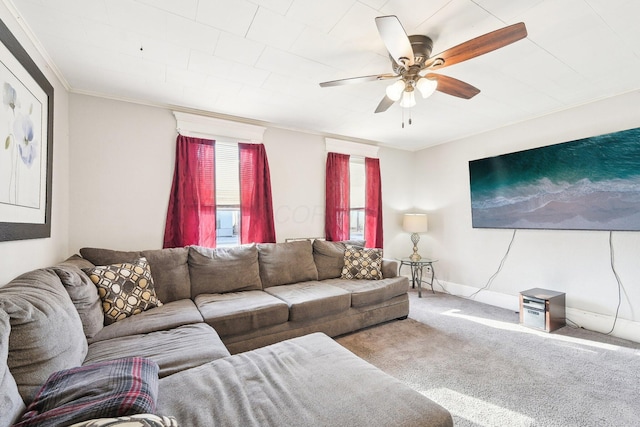 living area featuring baseboards, carpet flooring, a ceiling fan, and ornamental molding