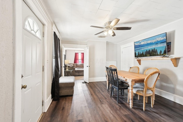 dining room featuring crown molding, visible vents, a ceiling fan, baseboards, and dark wood-type flooring