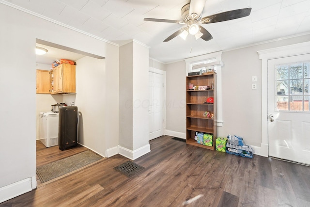 interior space featuring washer and clothes dryer, a ceiling fan, baseboards, ornamental molding, and dark wood finished floors