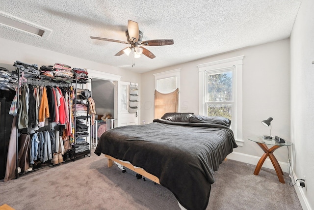 carpeted bedroom with attic access, baseboards, a ceiling fan, and a textured ceiling