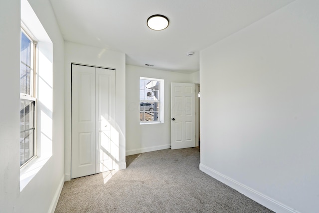 unfurnished bedroom featuring light carpet, a closet, visible vents, and baseboards