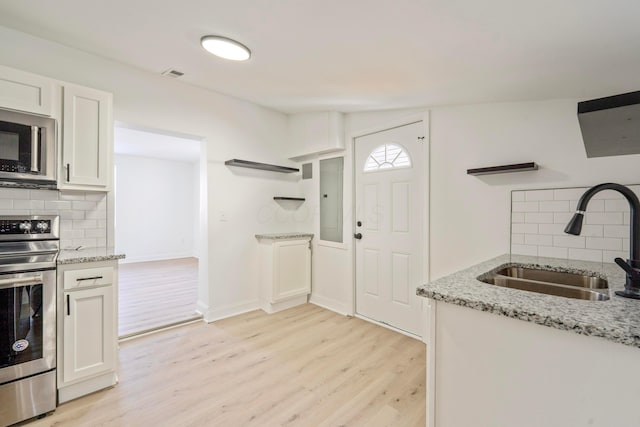 kitchen featuring a sink, white cabinets, appliances with stainless steel finishes, light wood-type flooring, and open shelves