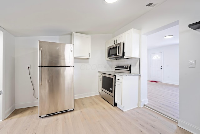 kitchen featuring light wood-style flooring, stainless steel appliances, visible vents, white cabinets, and tasteful backsplash