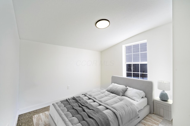 bedroom featuring baseboards, vaulted ceiling, and light colored carpet