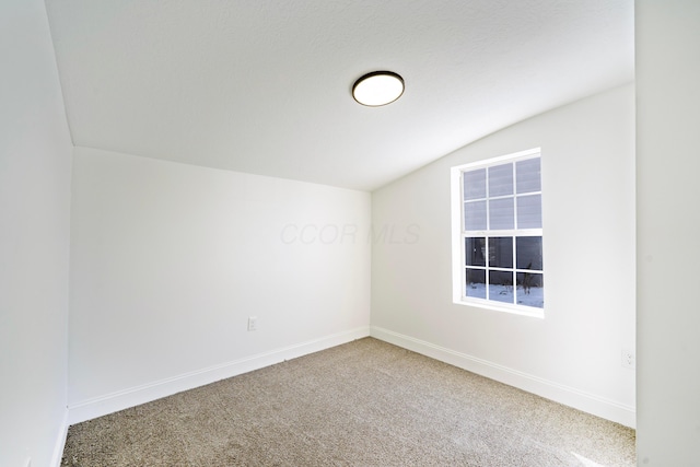 carpeted empty room with lofted ceiling and baseboards