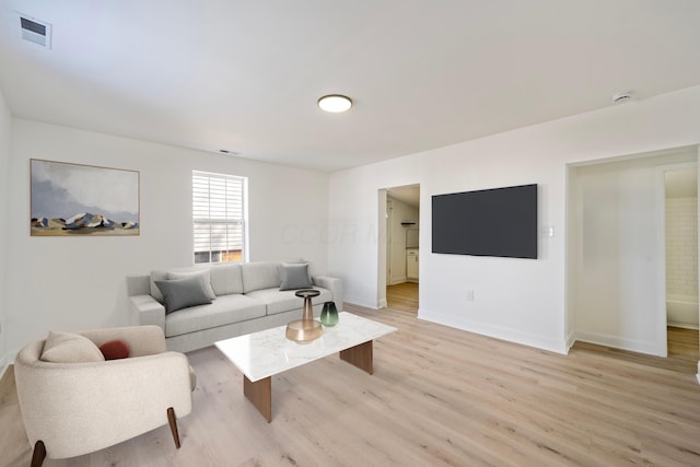 living area featuring light wood finished floors, visible vents, and baseboards