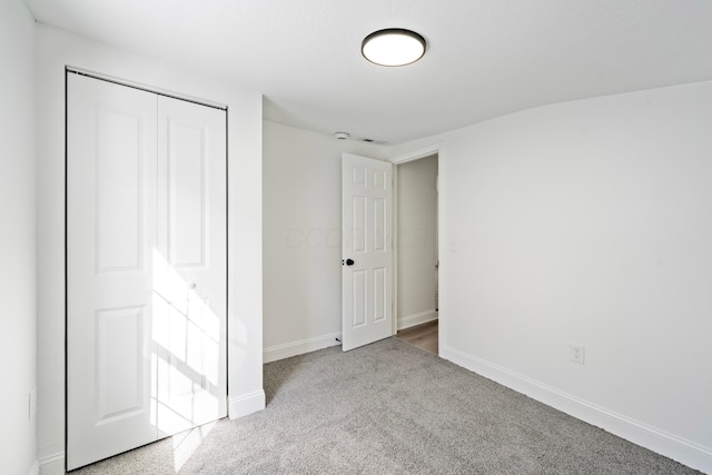 unfurnished bedroom featuring a closet, light colored carpet, and baseboards