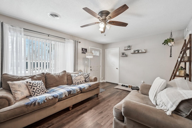 living area featuring visible vents, ceiling fan, a textured ceiling, and wood finished floors