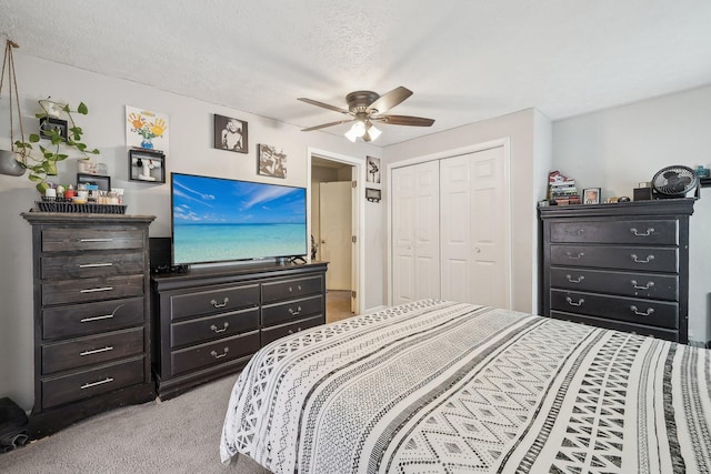 bedroom with a textured ceiling, a ceiling fan, a closet, and light carpet