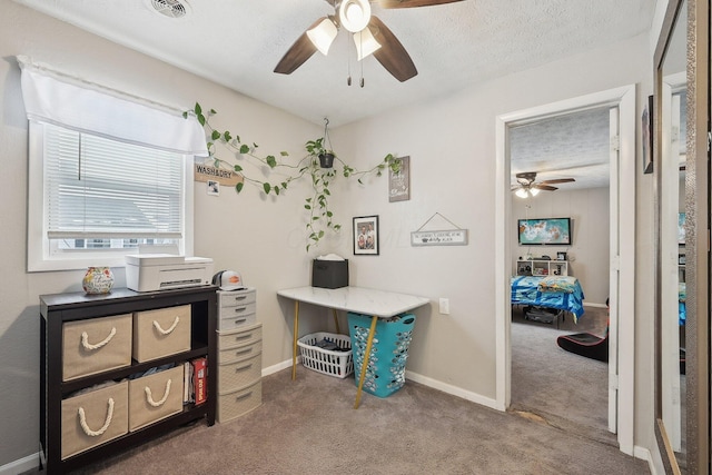 carpeted home office with a textured ceiling, ceiling fan, visible vents, and baseboards