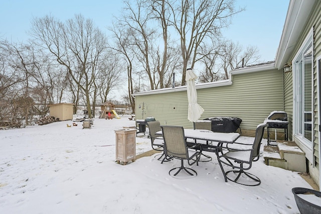 snow covered patio featuring a grill, outdoor dining area, and entry steps