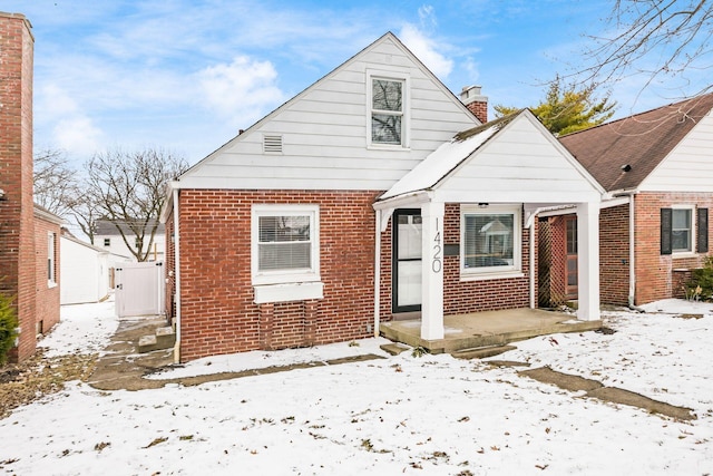 bungalow featuring brick siding and a chimney