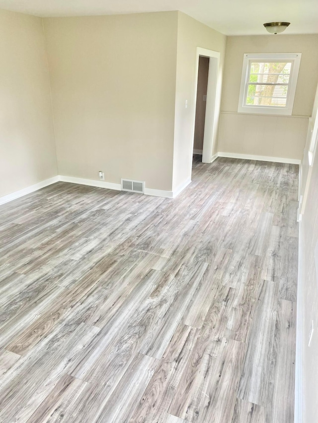 empty room featuring visible vents, light wood-style flooring, and baseboards