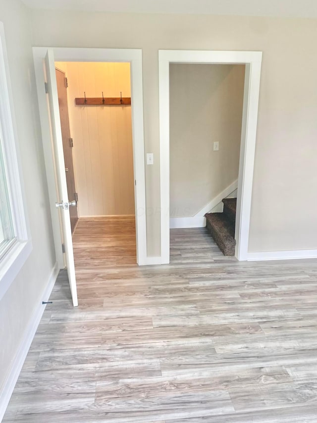 unfurnished room with light wood-style floors, baseboards, and stairs