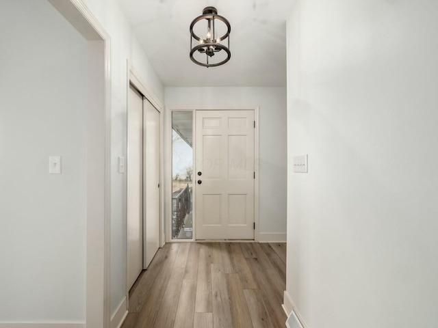 corridor with a notable chandelier, wood finished floors, and baseboards