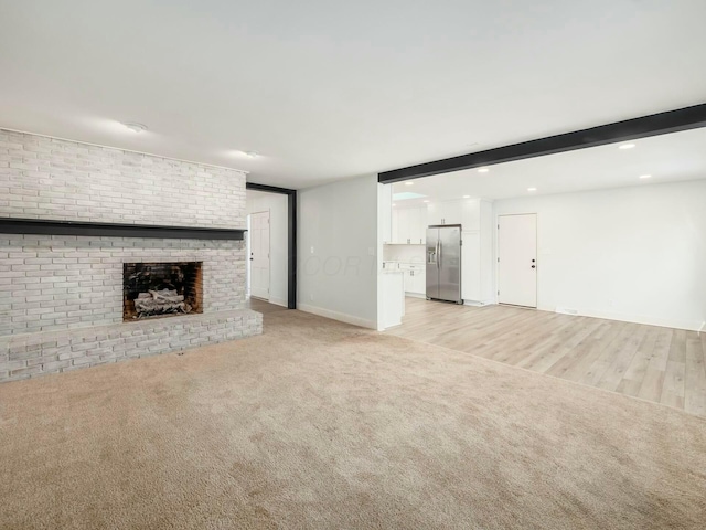 unfurnished living room with light carpet, a fireplace, beam ceiling, and recessed lighting