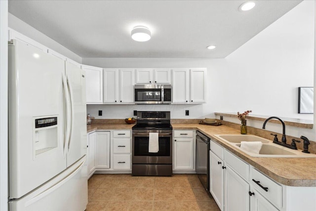 kitchen featuring appliances with stainless steel finishes, light countertops, a sink, and white cabinetry