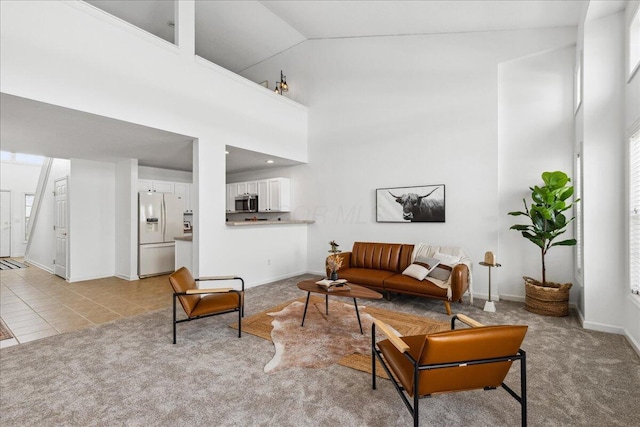 living area with high vaulted ceiling, light colored carpet, baseboards, and light tile patterned floors