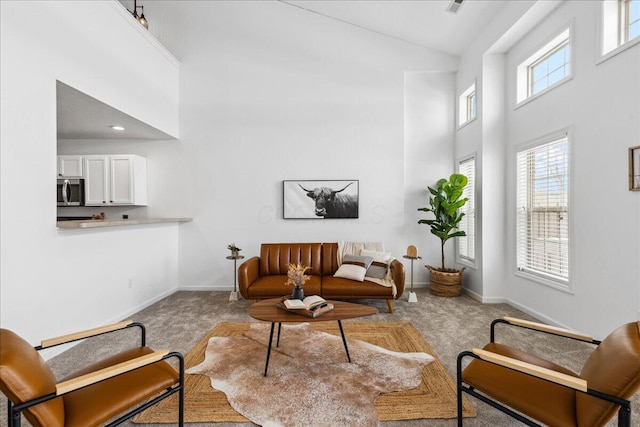 living area featuring baseboards, high vaulted ceiling, and light colored carpet