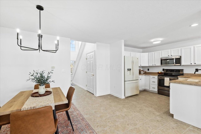 kitchen featuring baseboards, white cabinets, appliances with stainless steel finishes, hanging light fixtures, and light countertops