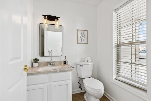 bathroom with a wealth of natural light, vanity, toilet, and tile patterned floors