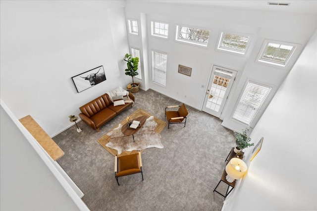 carpeted living area with a towering ceiling and visible vents