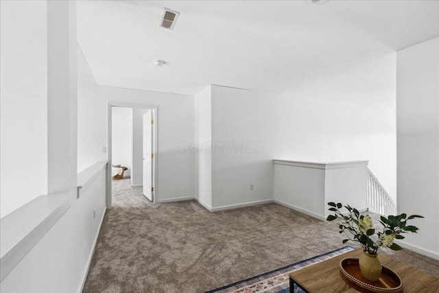 hallway with baseboards, light carpet, visible vents, and an upstairs landing