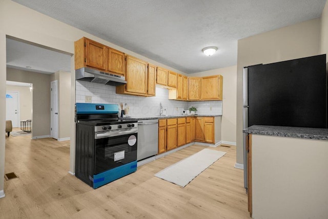 kitchen featuring light wood-type flooring, stainless steel appliances, and backsplash