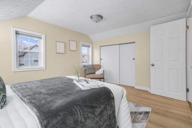 bedroom featuring a closet, lofted ceiling, and light hardwood / wood-style flooring