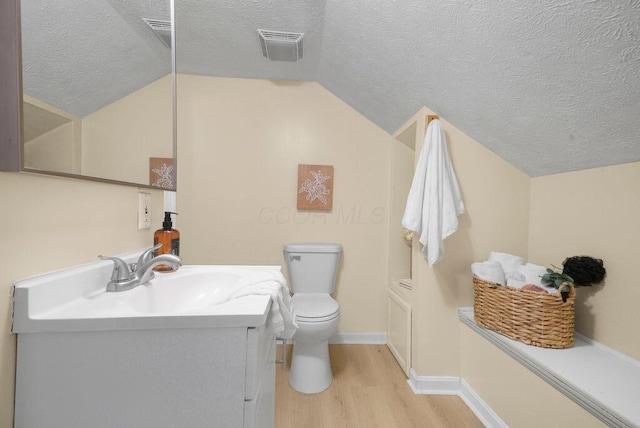 bathroom with hardwood / wood-style flooring, lofted ceiling, toilet, a textured ceiling, and vanity