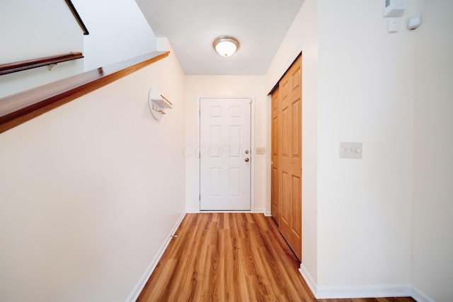 hallway featuring light wood-style flooring and baseboards