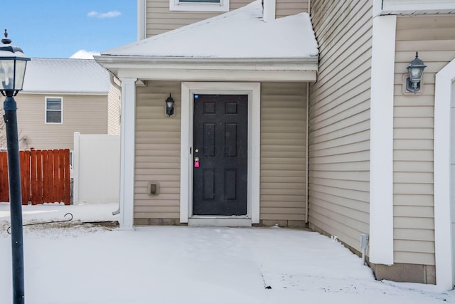 snow covered property entrance featuring fence