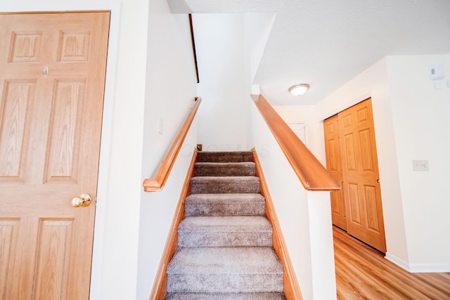 stairs with wood finished floors and baseboards