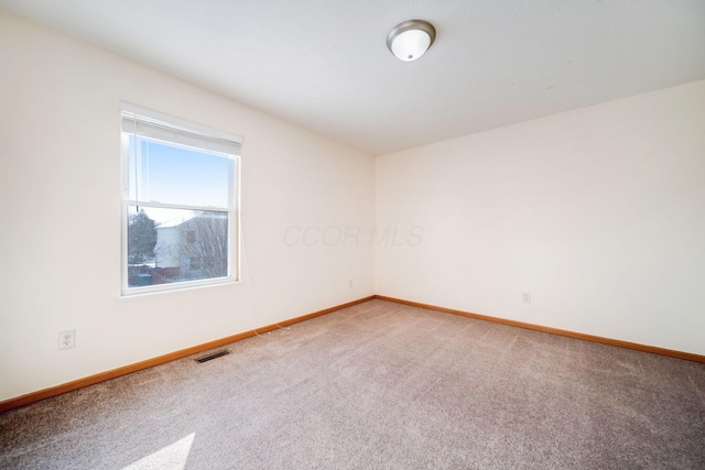 empty room featuring carpet, visible vents, and baseboards